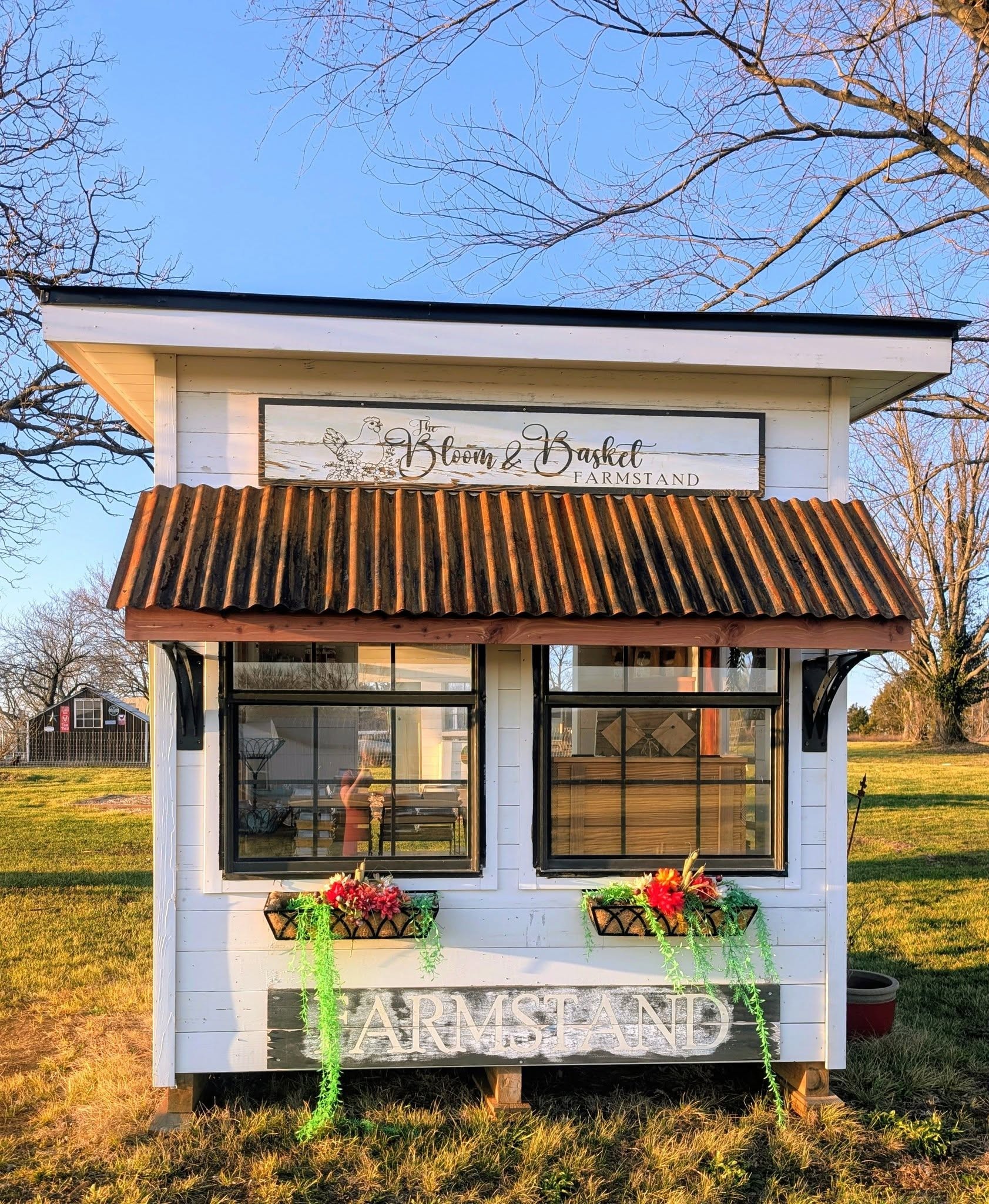 The white Bloom and Basket Farmstand photographed straight on, with its name above the front windows